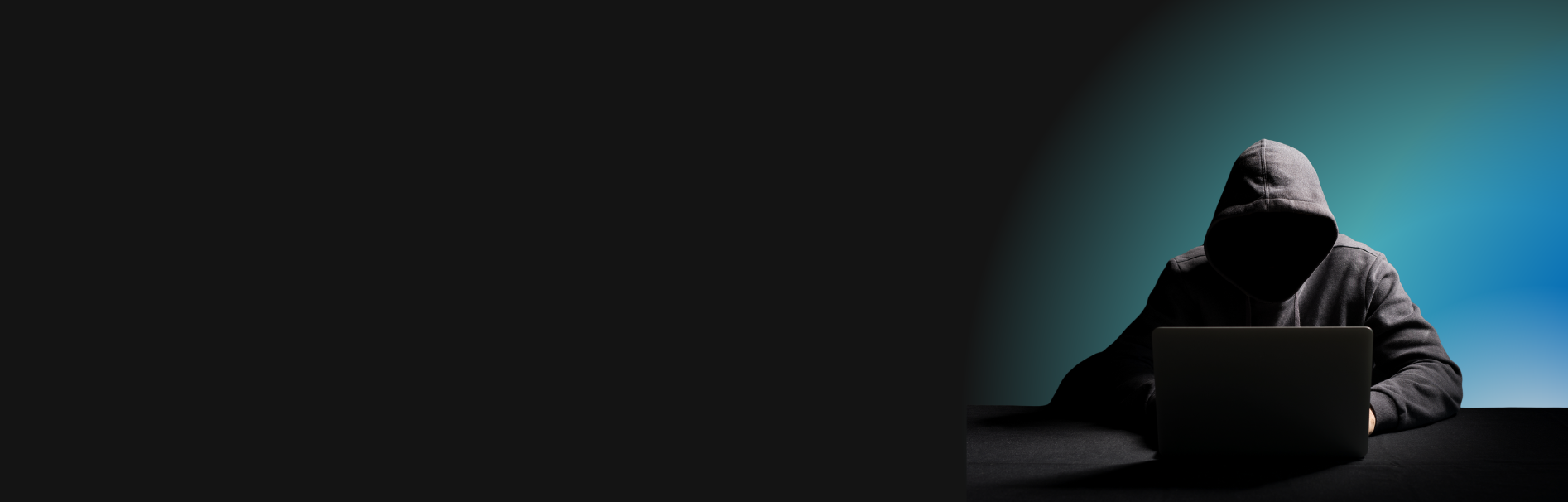 Silhueta de uma pessoa usando um capuz e sentada na frente de um laptop em uma mesa, com iluminação que projeta uma aura azulada sobre metade do fundo, enquanto a outra metade permanece escura, sugerindo atividades ocultas ou clandestinas relacionadas à cibersegurança.